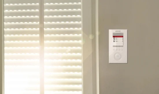 Innenansicht eines Raumes mit geschlossenen Jalousien und einer Steuerungseinheit an der Wand